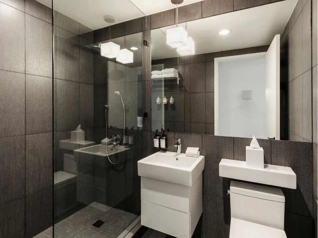 Salle de bain avec murs gris, équipements blancs et douche en verre.