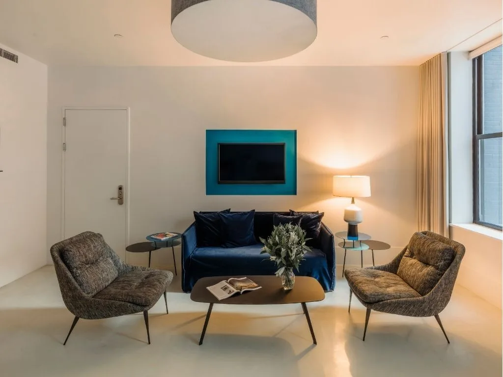 Salon avec canapé bleu, deux fauteuils et une table basse.