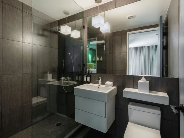 Modern bathroom with gray walls, white fixtures, and a glass shower.