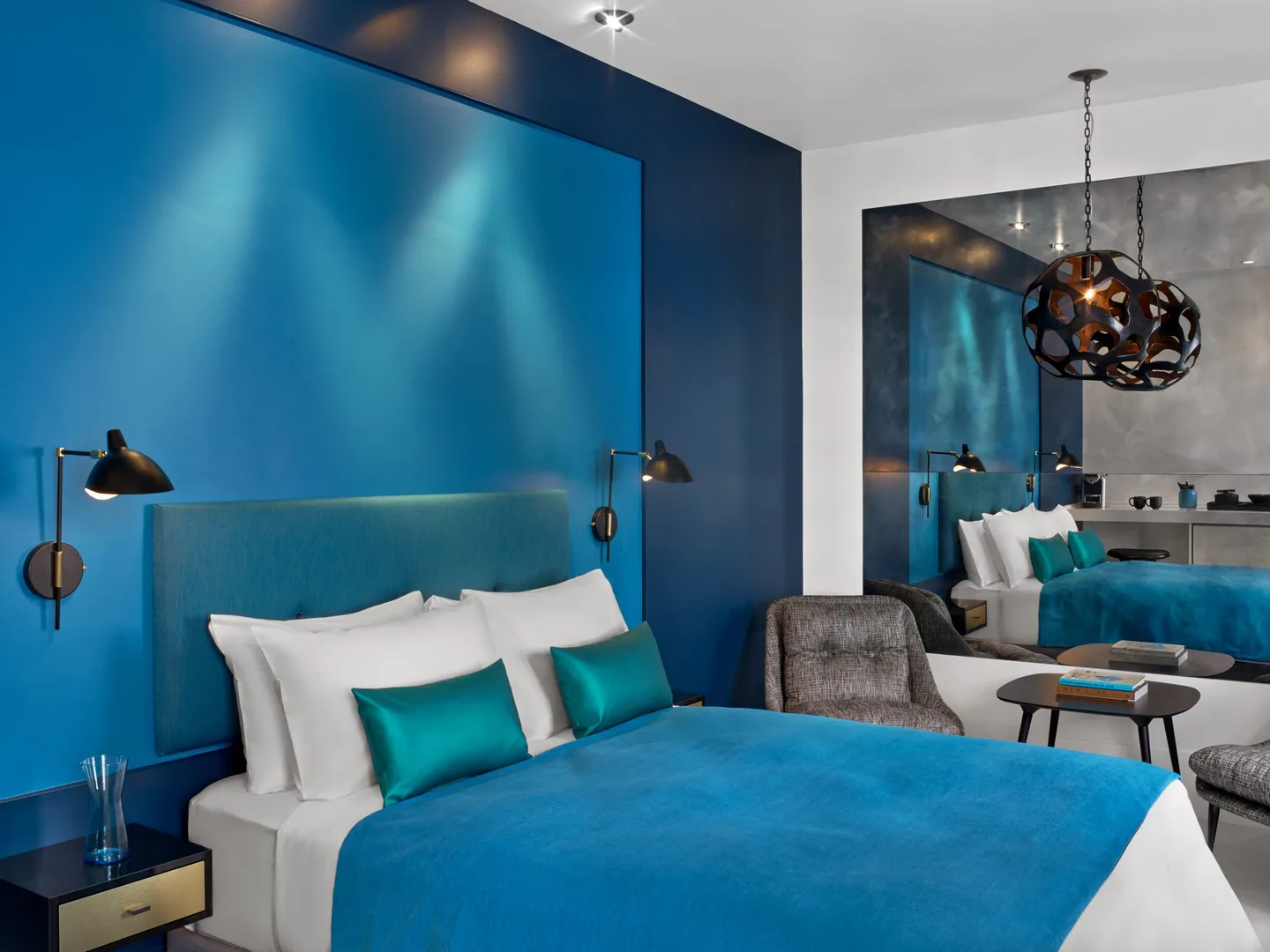 Queen Studio with queen bed, teal accent wall and sculptural pendant lights