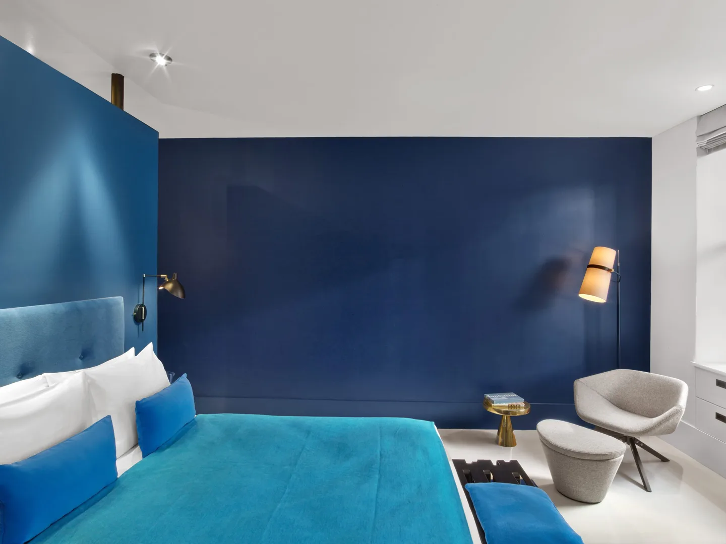 King bed with navy accent wall and reading chair