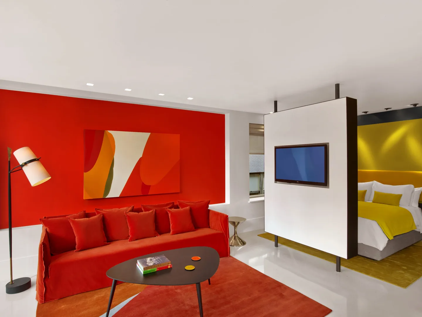Penthouse Suite living room with red velvet sofa and view into the yellow bedroom